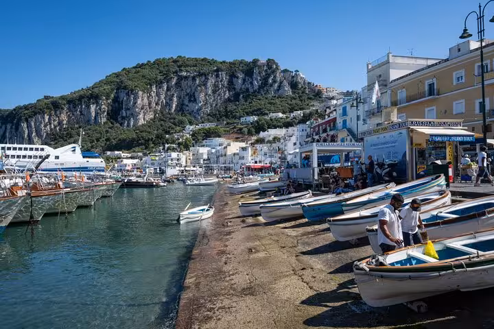 Picturesque Capri harbor with colorful boats, vibrant waterfront, and stunning cliffs, ideal for full-day island tours.