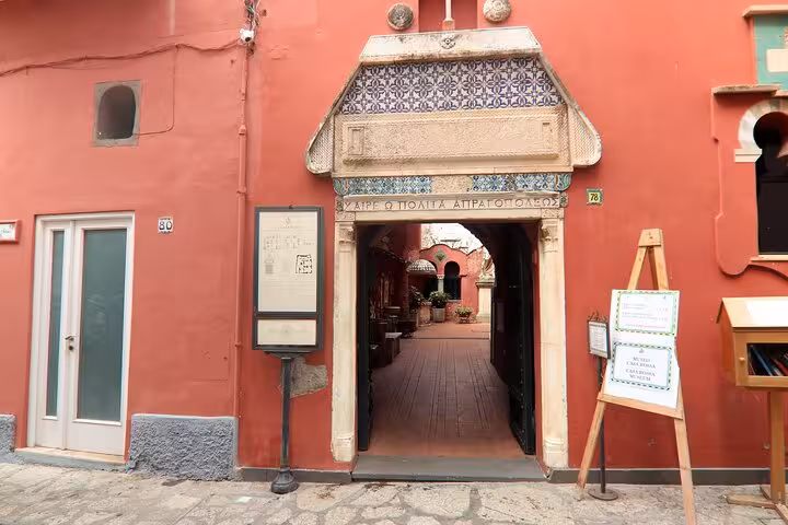 Entrance to a charming historical building in Capri, featuring vibrant red walls and intricate architectural details.