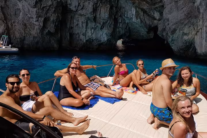 Group of tourists relaxing on a boat deck near a cave during a Capri Island excursion from Amalfi.