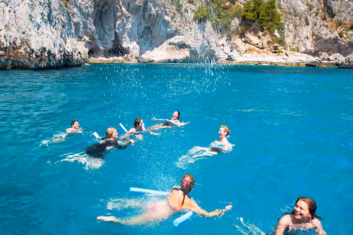 Group enjoying a swim in clear blue waters near Capri Island on a day excursion from Sorrento.