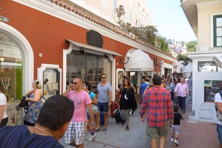 Bustling shopping street in Capri featuring luxury brands and lively pedestrian activity.