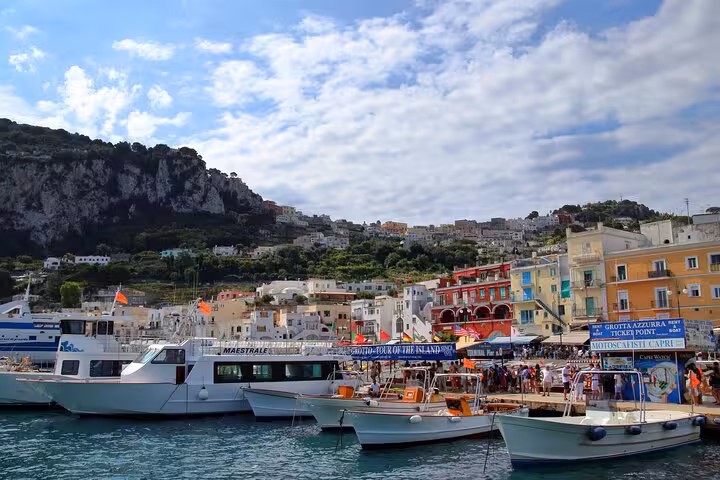 Vibrant marina in Capri bustling with boats and colorful buildings, showcasing the lively coastal atmosphere.