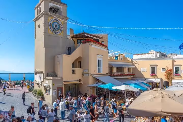 Vibrant Piazza Umberto I bustling with tourists, cafes, and historic clock tower during a private tour of Capri.