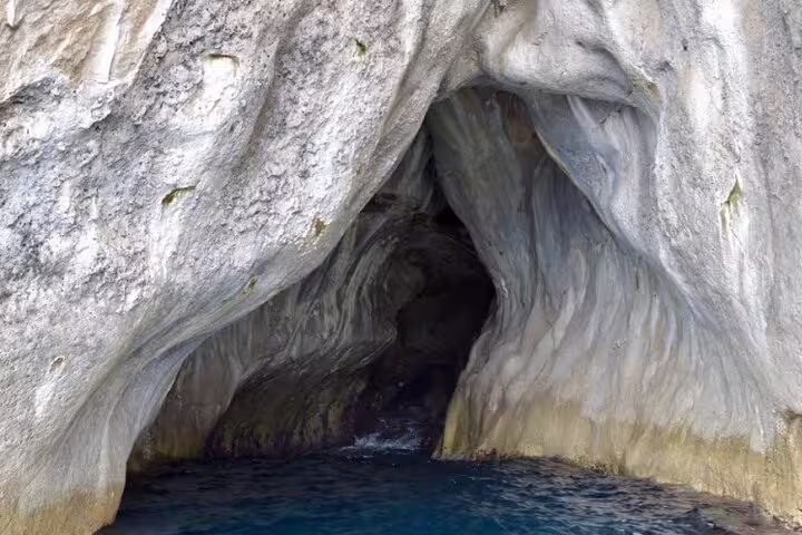 Private boat tour Sea Day exploring a Capri sea cave with crystal-blue water and sculpted limestone walls
