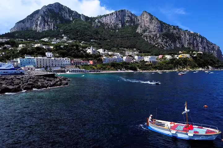 Private boat tour full day along Capri coastline with sea views, colorful harbor and dramatic cliffs