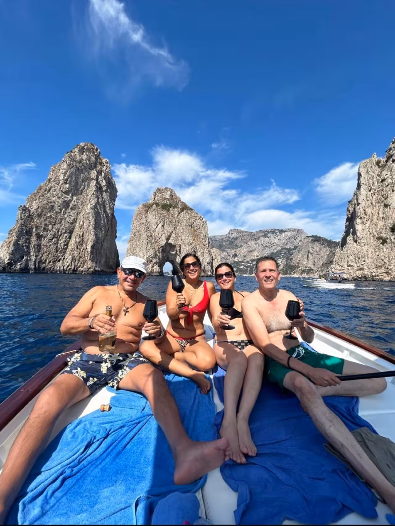 Guests toasting on a 6-hour private Capri boat tour by the Faraglioni rocks, swim stops and hidden coves