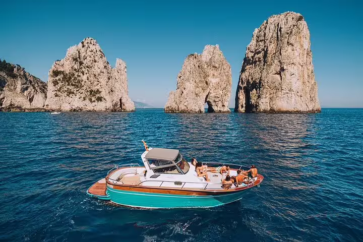 Turquoise private boat near Faraglioni rocks on a Capri island boat tour, Italy