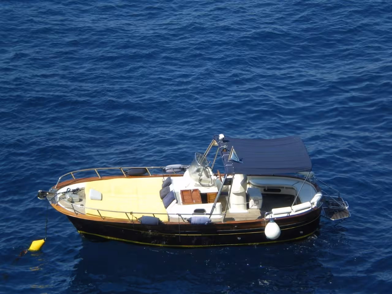 Capri 6-hour private boat tour with classic motorboat cruising on deep blue sea for swimming and relaxing