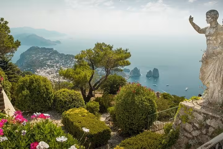 Lush gardens with a statue overlook Capri's stunning landscape, providing a serene moment on the private guided tour.