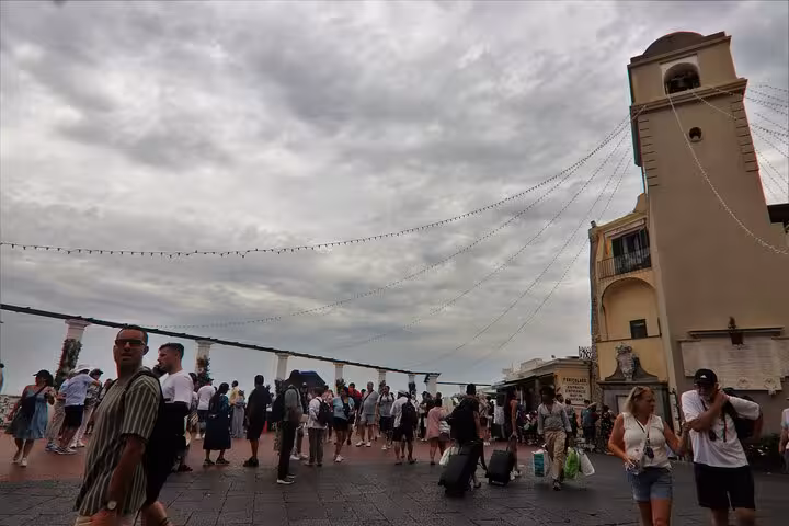 Bustling square in Capri with tourists and historic architecture, showcasing lively atmosphere of Sorrento tour.