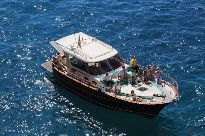 Tourists enjoying a scenic Capri sunset boat tour on a luxury vessel in the Mediterranean Sea.