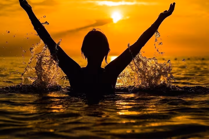 Joyful person splashing in the sea at sunset during a Capri boat tour adventure.