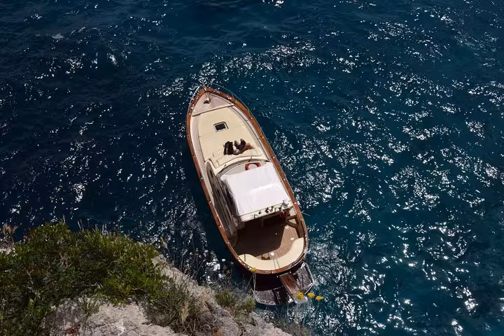 Aerial view of a boat cruising the vibrant blue waters on the Capri Sunset Escape from Sorrento.