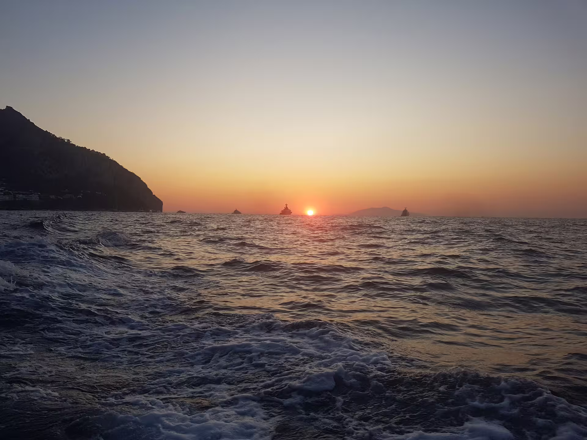 Sunset over open sea with yachts and coastal cliffs, From Dusk Till Night immersive night experience tour