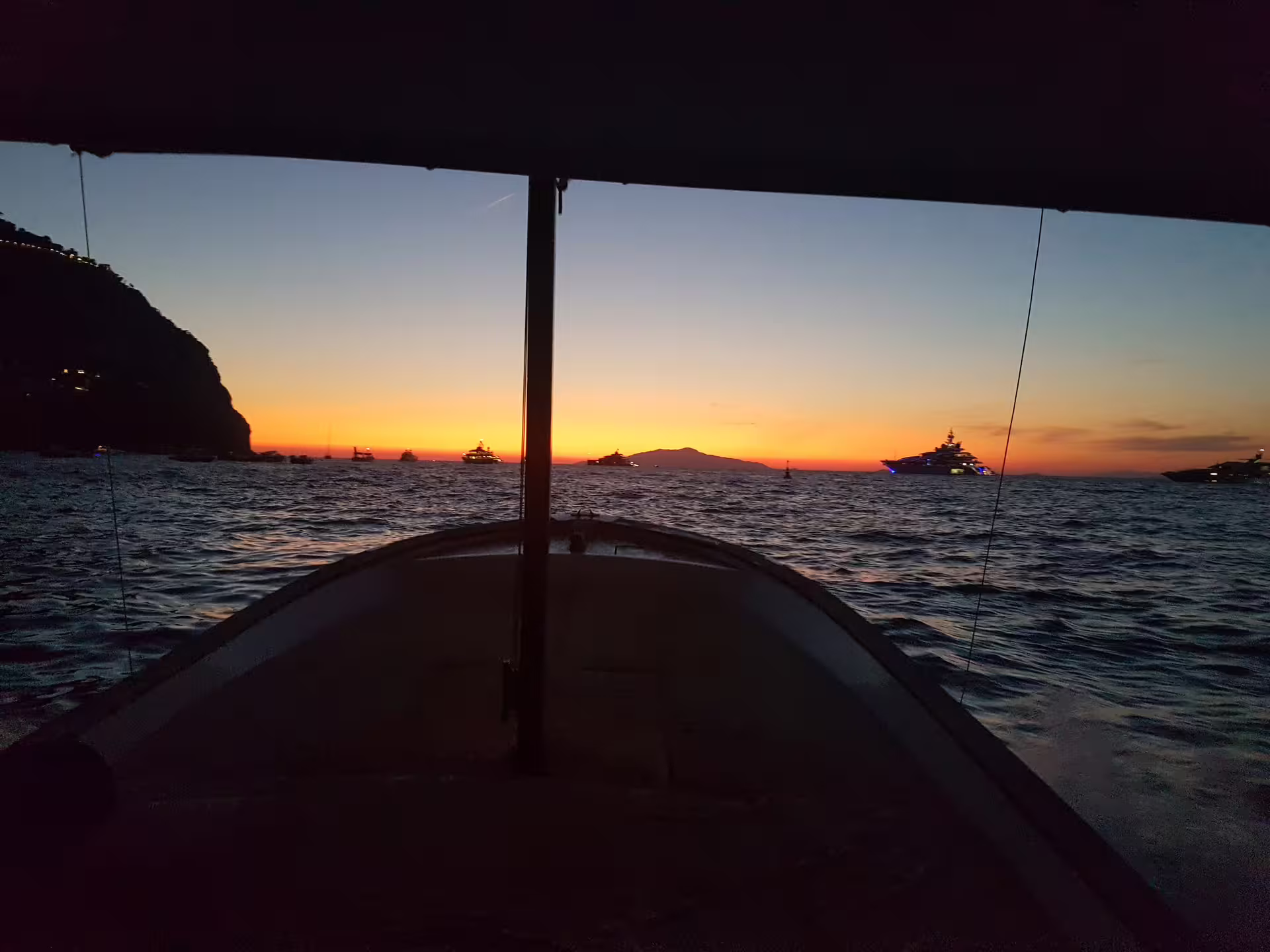 Twilight cruise view from boat toward glowing horizon and yachts, From Dusk Till Night night tour