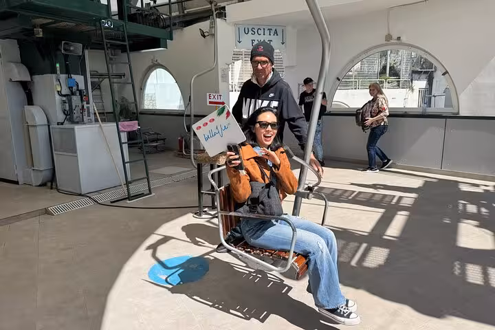 A joyful woman ready for the chairlift ride at the Capri tour departure point, showcasing excitement and adventure.