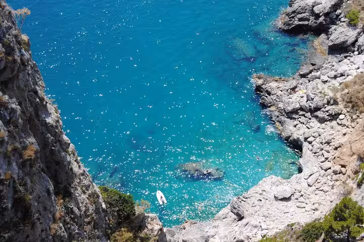 Stunning aerial view of Capri's crystal-clear turquoise waters and rocky coastline, ideal for scenic boat tours.