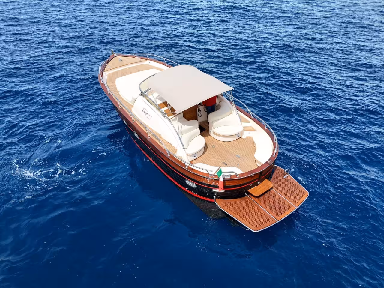 Classic wooden motorboat cruising blue sea on Capri one-day boat tour, ideal for island sightseeing and swim stops