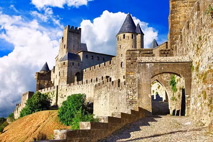 Stunning view of Carcassonne's medieval castle walls and towers under a vibrant blue sky, perfect for a guided tour.