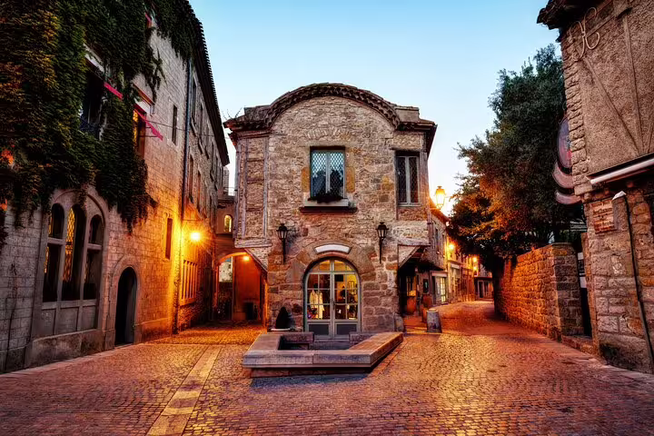 Cobblestone square with medieval stone buildings and warm glowing lanterns in Carcassonne at dusk