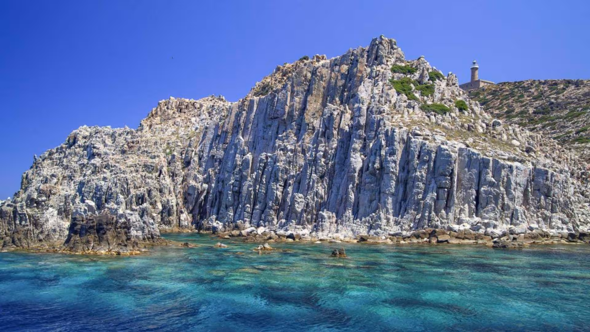 Majestic cliffs rising from azure waters near Carloforte, highlighting rugged landscapes on a dinghy tour.