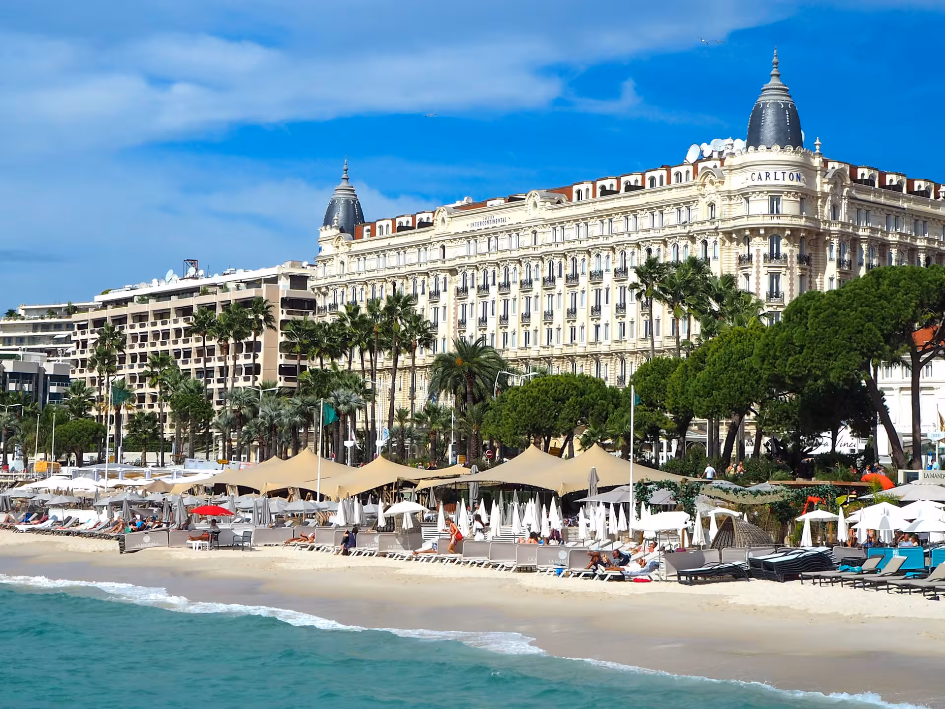 Carlton Hotel Cannes beachfront with sun loungers and umbrellas on the French Riviera