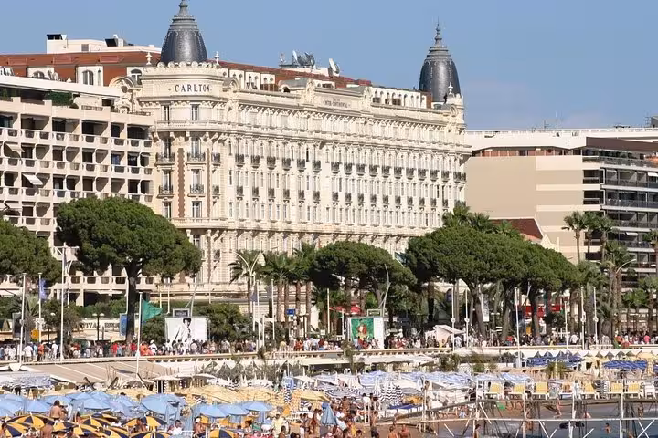 Carlton Hotel Cannes beachfront promenade with luxury beach clubs and palm trees on French Riviera