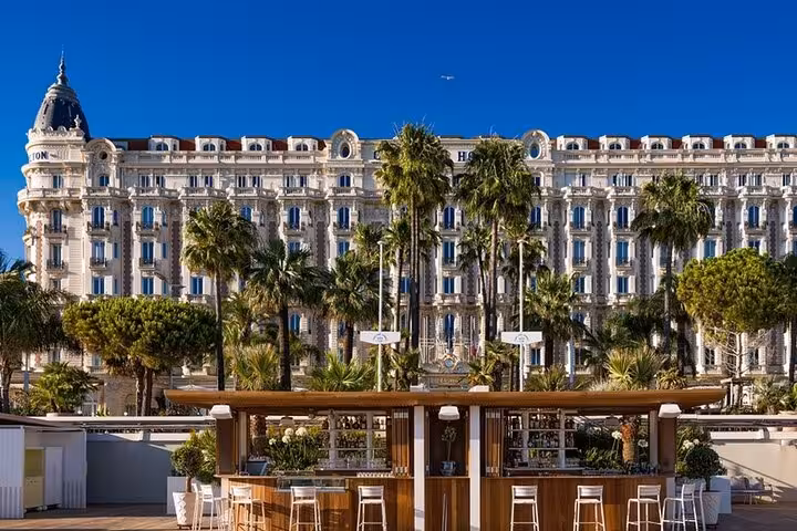 Carlton Hotel Cannes with palm trees and outdoor beach bar on the French Riviera