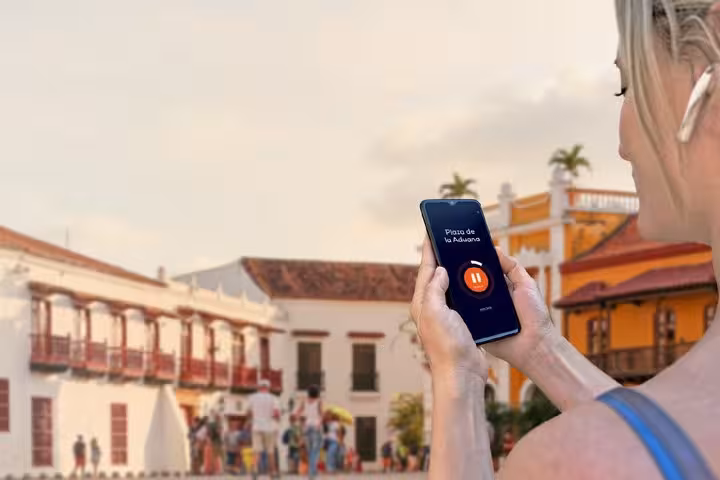 Tourist using audio tour app at Plaza de la Aduana in Cartagena's historic walled city