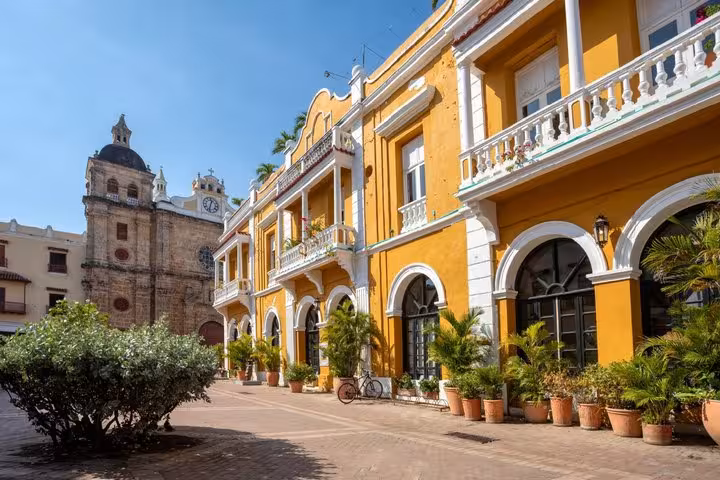 Colonial yellow building with white balconies and arched windows in Cartagena's historic plaza