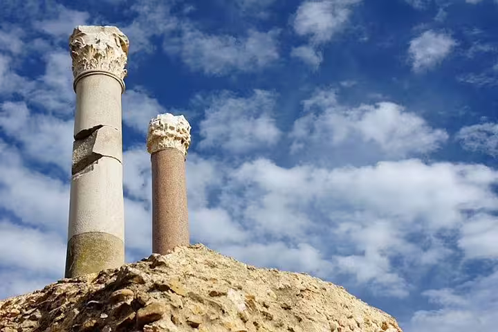 Ancient Roman columns stand against a bright blue sky in the historic ruins of Carthage, a highlight of the Carthage tour.