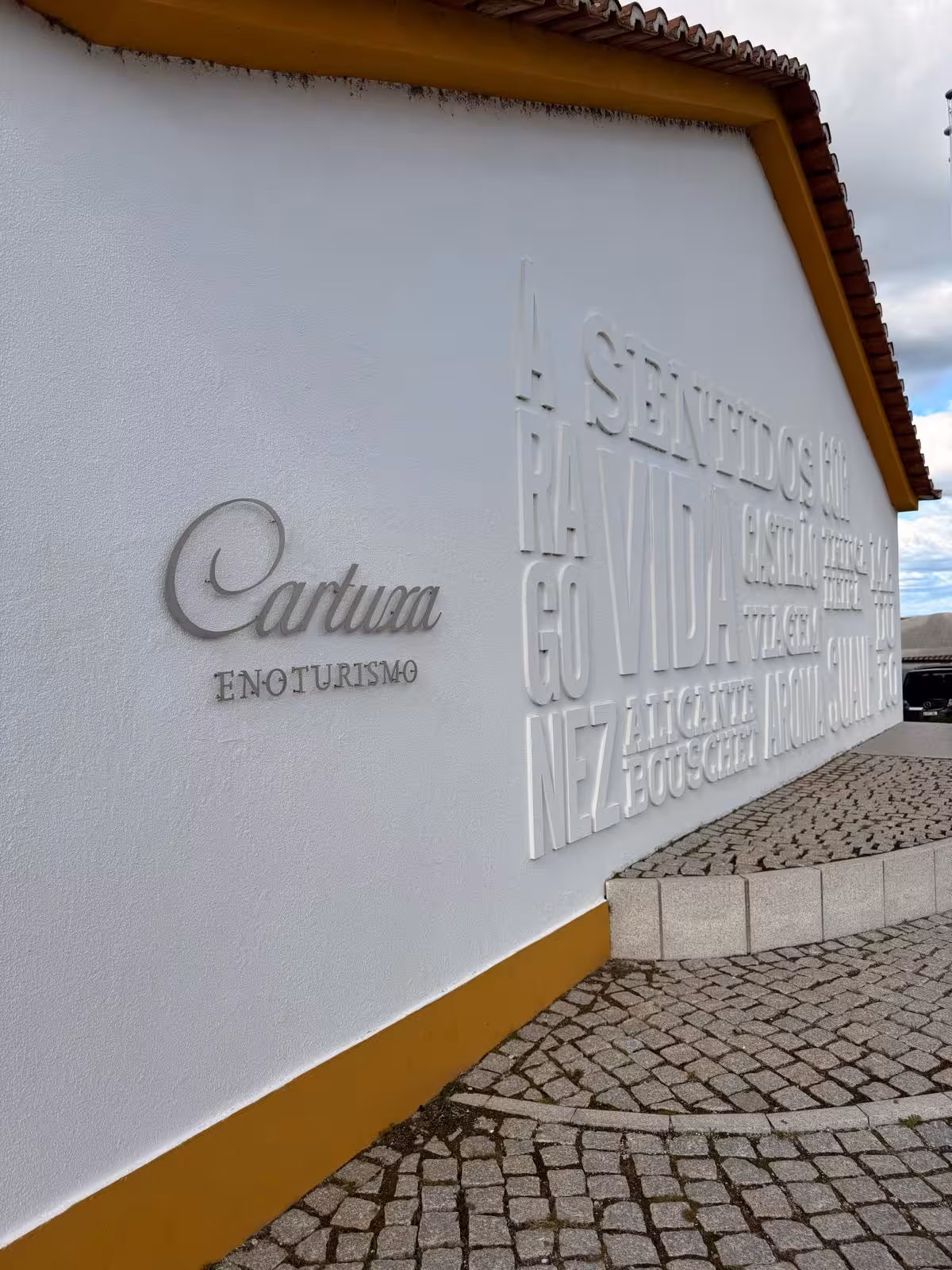 Cartuxa Enoturismo wall sign on a sunny day, highlighting wine tourism in Évora's historic setting.