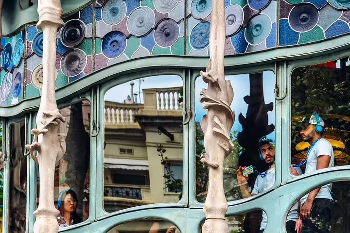 Visitors exploring Casa Batlló's vibrant facade with colorful mosaics and unique window designs in Barcelona.