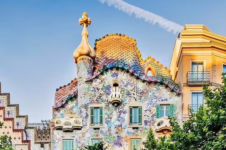 Vibrant facade of Casa Batlló in Barcelona, showcasing Gaudi's colorful mosaic design under a clear blue sky.