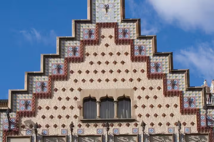 Intricate facade of a modernist building in Barcelona, showcasing geometric patterns and colorful tiles under a blue sky.