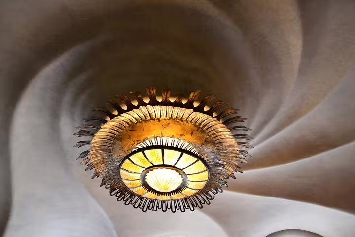 Intricate spiral ceiling design with ornate chandelier inside Casa Batlló, highlighting Gaudí's artistic flair.