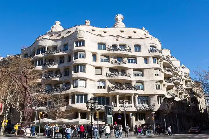 Visitors admire the unique undulating exterior of Casa Milà in Barcelona, a highlight of the city and wine cellar tour.