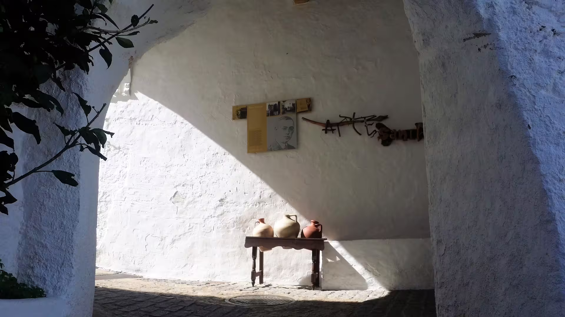 Whitewashed Casares corner with clay pots and museum-style wall display, visited on private trip with pickup