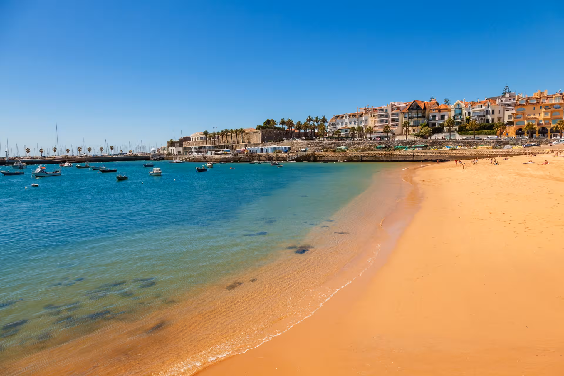 Scenic view of golden sands and turquoise waters at Cascais Beach, perfect for a relaxing day trip from Lisbon.