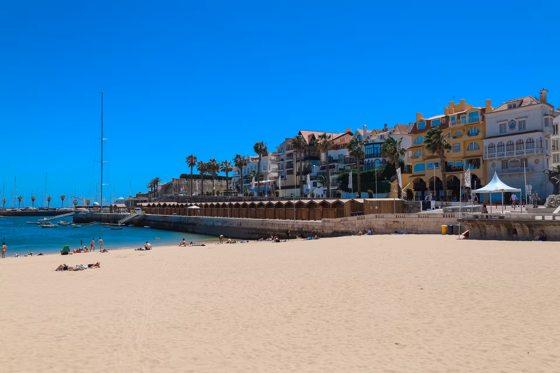 Sunny Cascais beach with scenic ocean views and vibrant coastal buildings, part of the Lisbon day tour experience.