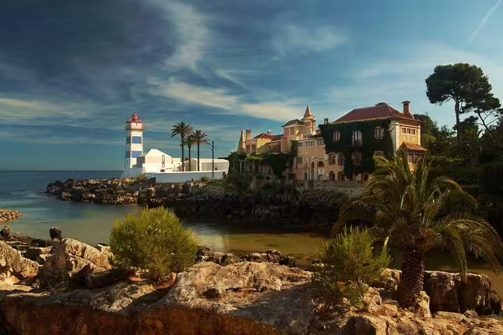 Scenic view of Cascais coastline with a lighthouse and historic architecture, perfect for a private Sintra and Cascais day tour.
