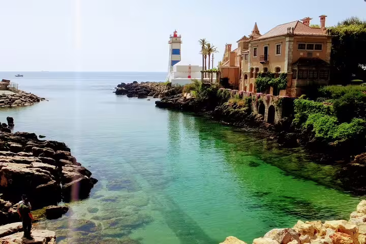Scenic view of Cascais coastline with historic lighthouse and villa, perfect for Sintra World Heritage and luxury private tours.
