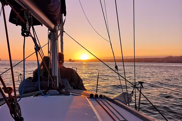 Couple silhouette with champagne at sunset on Cascais private cruise, featuring Clean & Safe and Safe Travels seals