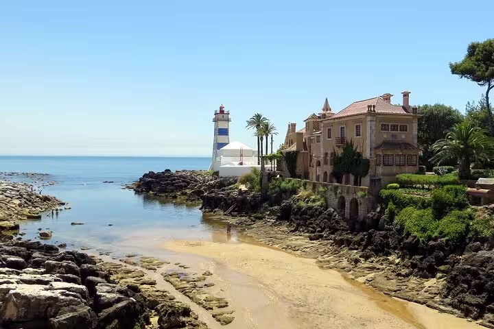Picturesque lighthouse and villa by the sea in Cascais, featured in the Sintra, Pena Palace, and Cape Roca tour.