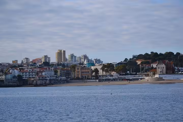 Cascais bay skyline viewed from a private sailing cruise, calm Atlantic waters and seaside promenade in Portugal
