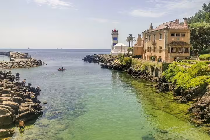 Scenic view of Cascais marina with historic architecture, lighthouse, and clear waters on a Sintra half-day tour from Lisbon.