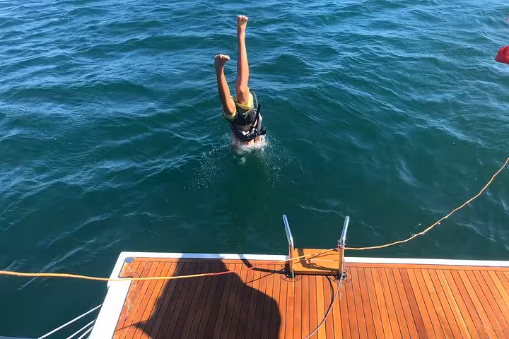 Guest diving into the Atlantic from a private yacht swim platform during a Cascais private sailing cruise