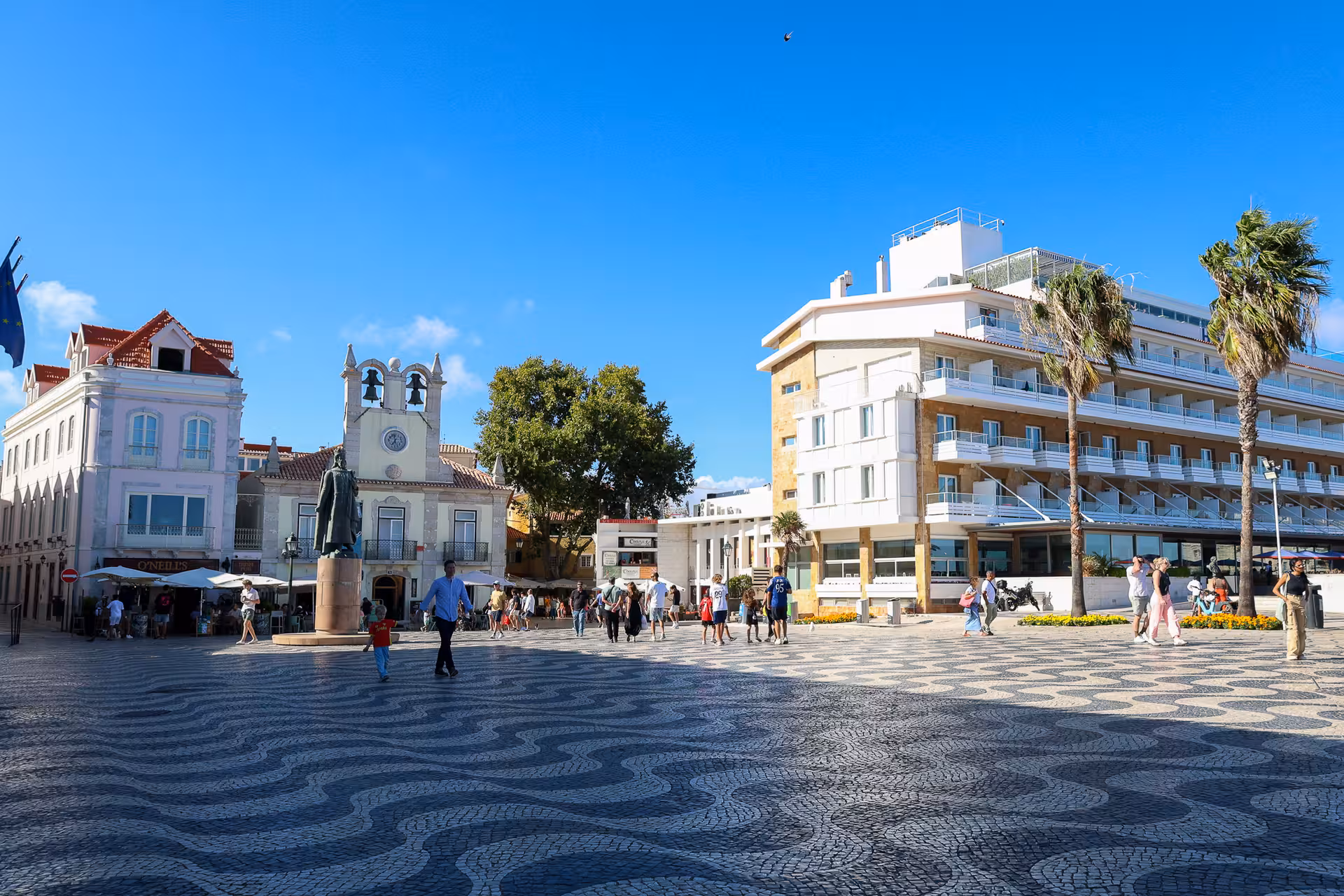 Sunny day at a lively square in Cascais, featuring historic buildings and people enjoying the vibrant atmosphere.