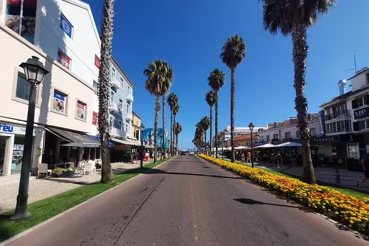 Picturesque Cascais street lined with palm trees and colorful shops under a clear blue sky.