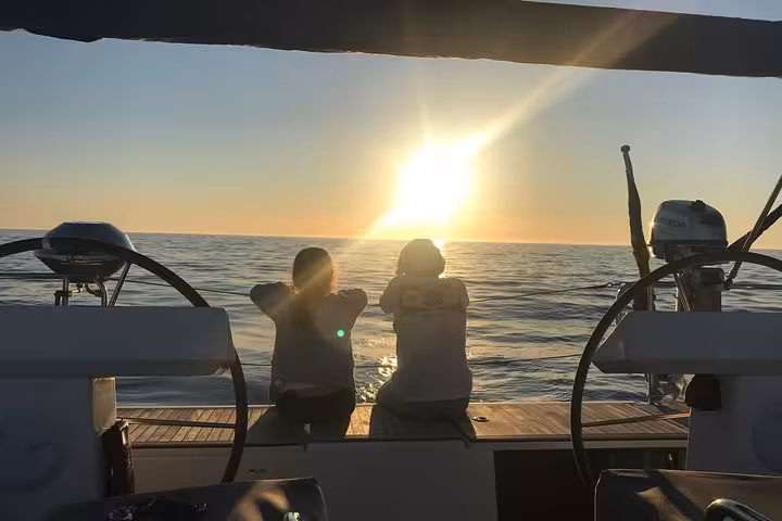 Guests relaxing on deck watching the Atlantic sunset on a private 2-hour Cascais cruise with drinks included
